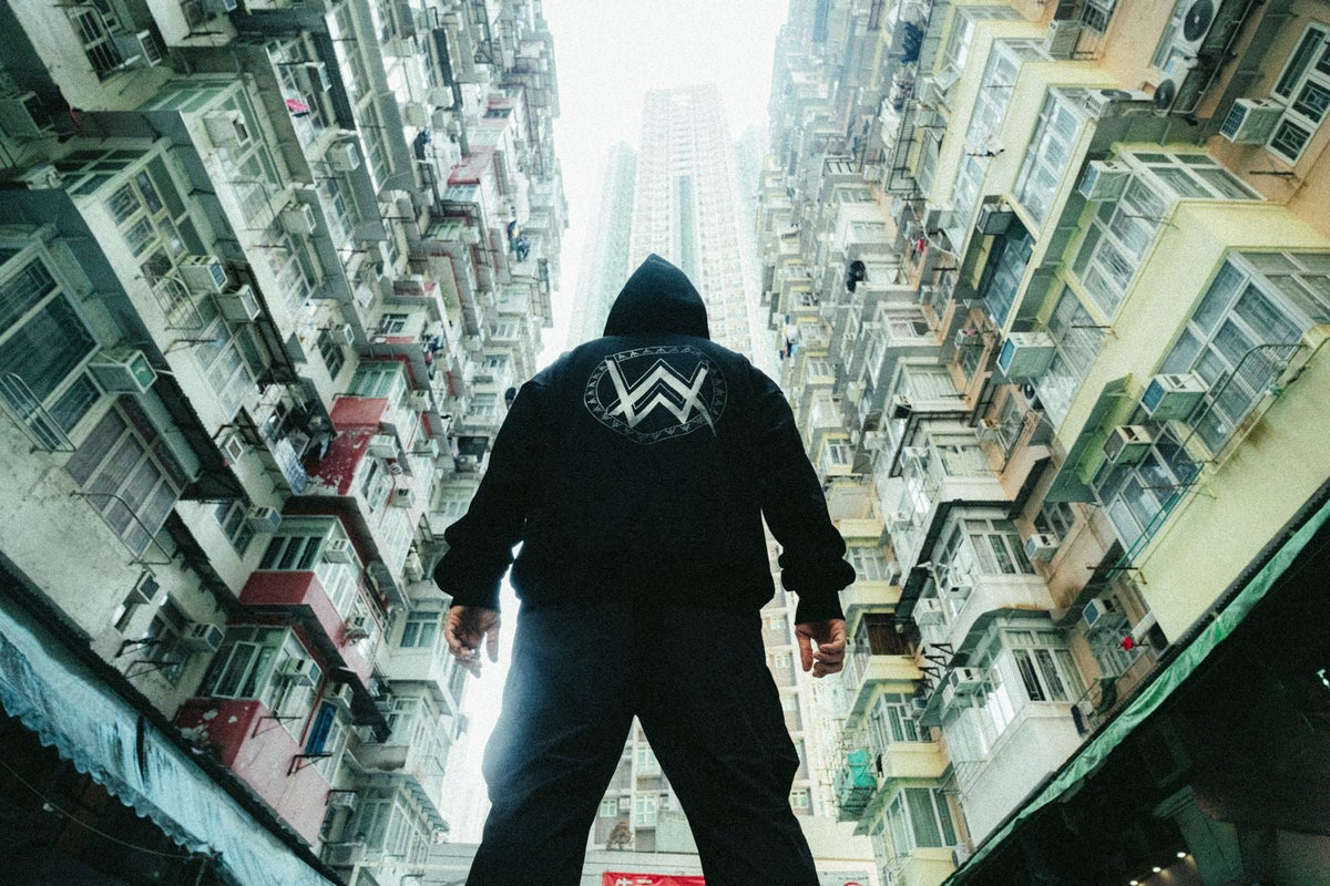 Alan Walker Core LV1 Windbreaker worn from behind between city towers, white AW crest on the black hood jacket