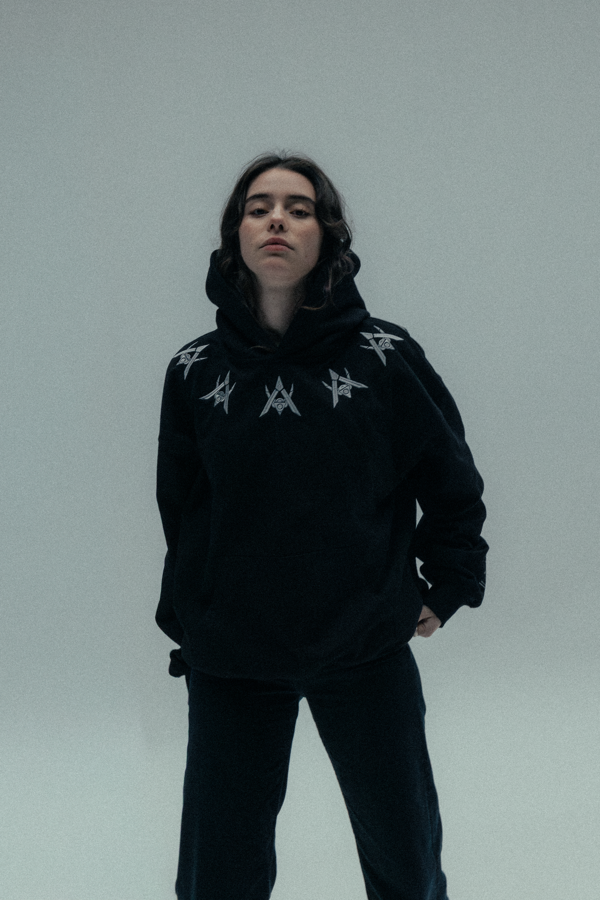 Alan Walker Watch The Drone Hoodie worn by a model with the hood up, black EDM streetwear with silver neck print