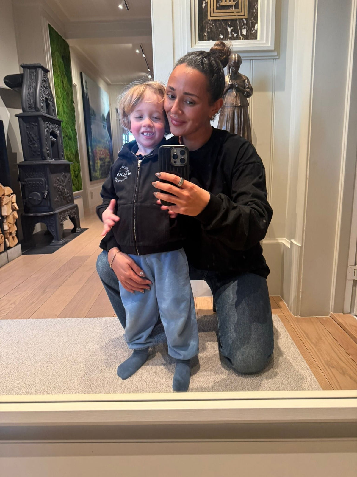 Alan Walker Monster Core Kids Zip Hoodie worn by a small child in a mirror selfie with mum, black zip-up EDM merch