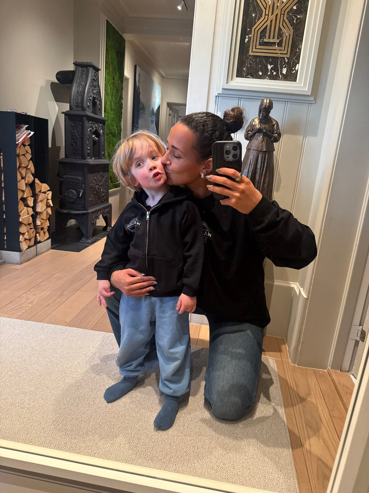 Alan Walker Monster Core Kids Zip Hoodie worn by a toddler in a hallway mirror selfie, black hooded zip-up merch