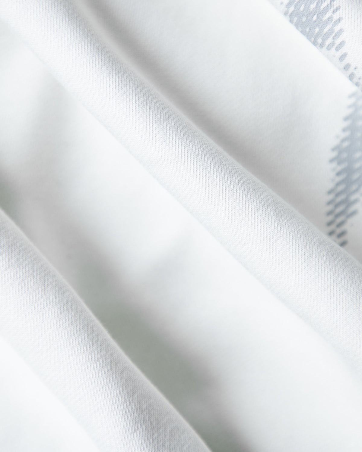 Alan Walker Faded Graffiti Hoodie off white fabric close-up, soft fleece folds beside the grey print edge