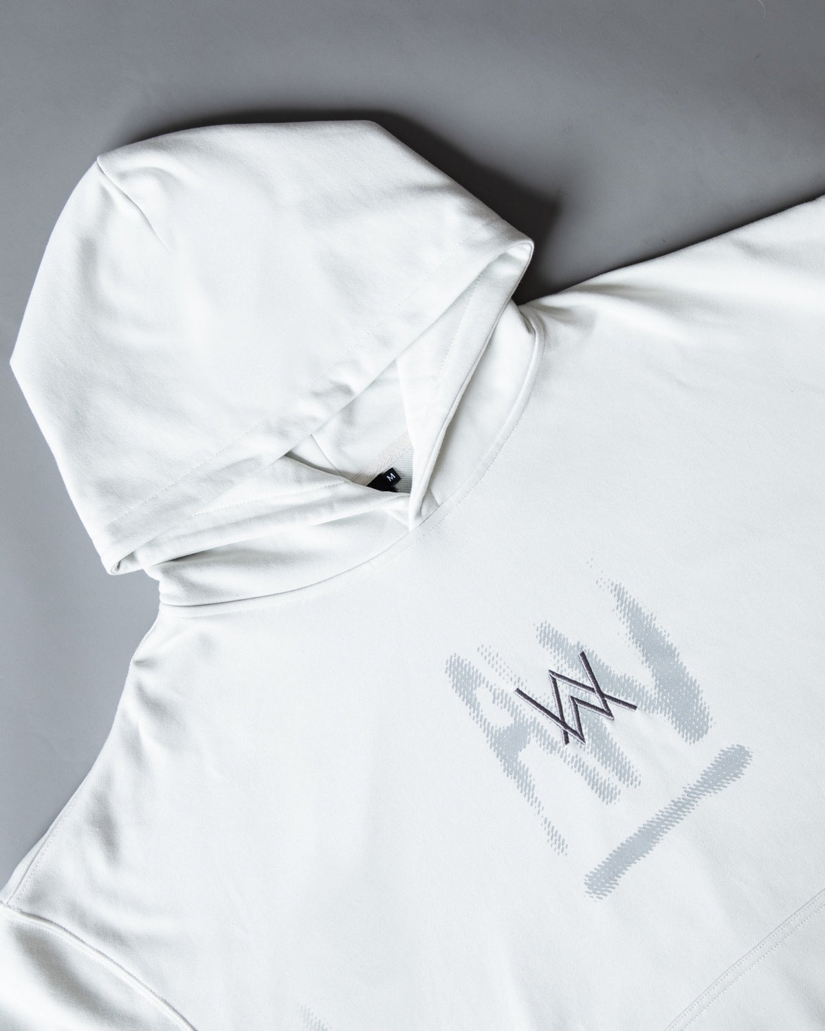 Alan Walker Faded Graffiti Hoodie off white folded at an angle, hood raised above the painted chest logo
