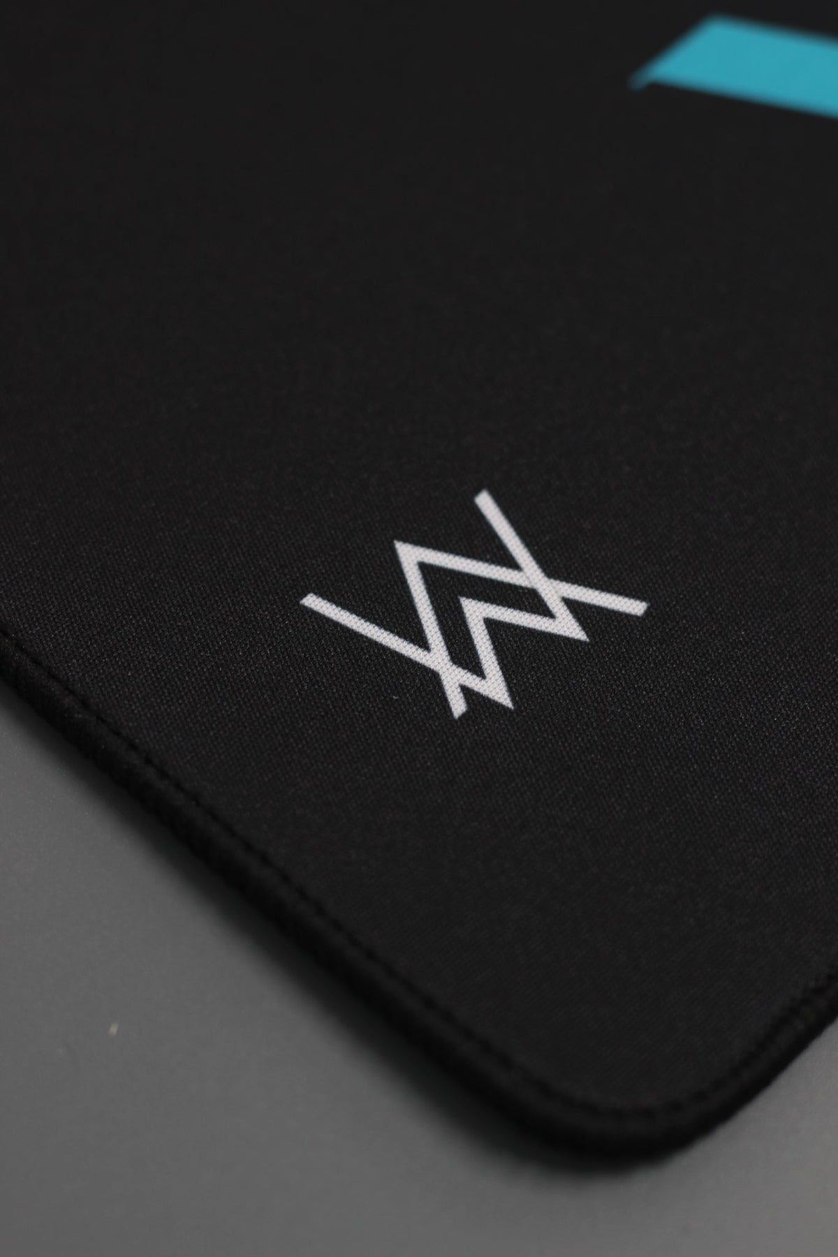 Alan Walker Gaming Mouse Pad detail with the white AW logo and stitched black edge on the desk mat