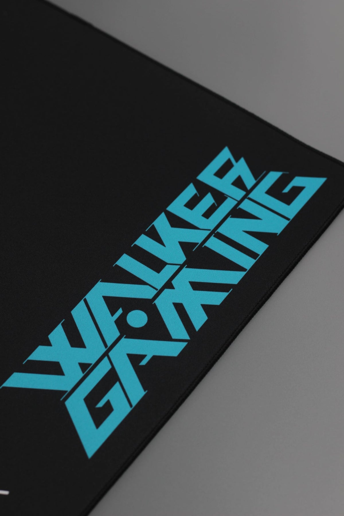 Alan Walker Gaming Mouse Pad corner close-up, cyan Walker Gaming print on the smooth black surface