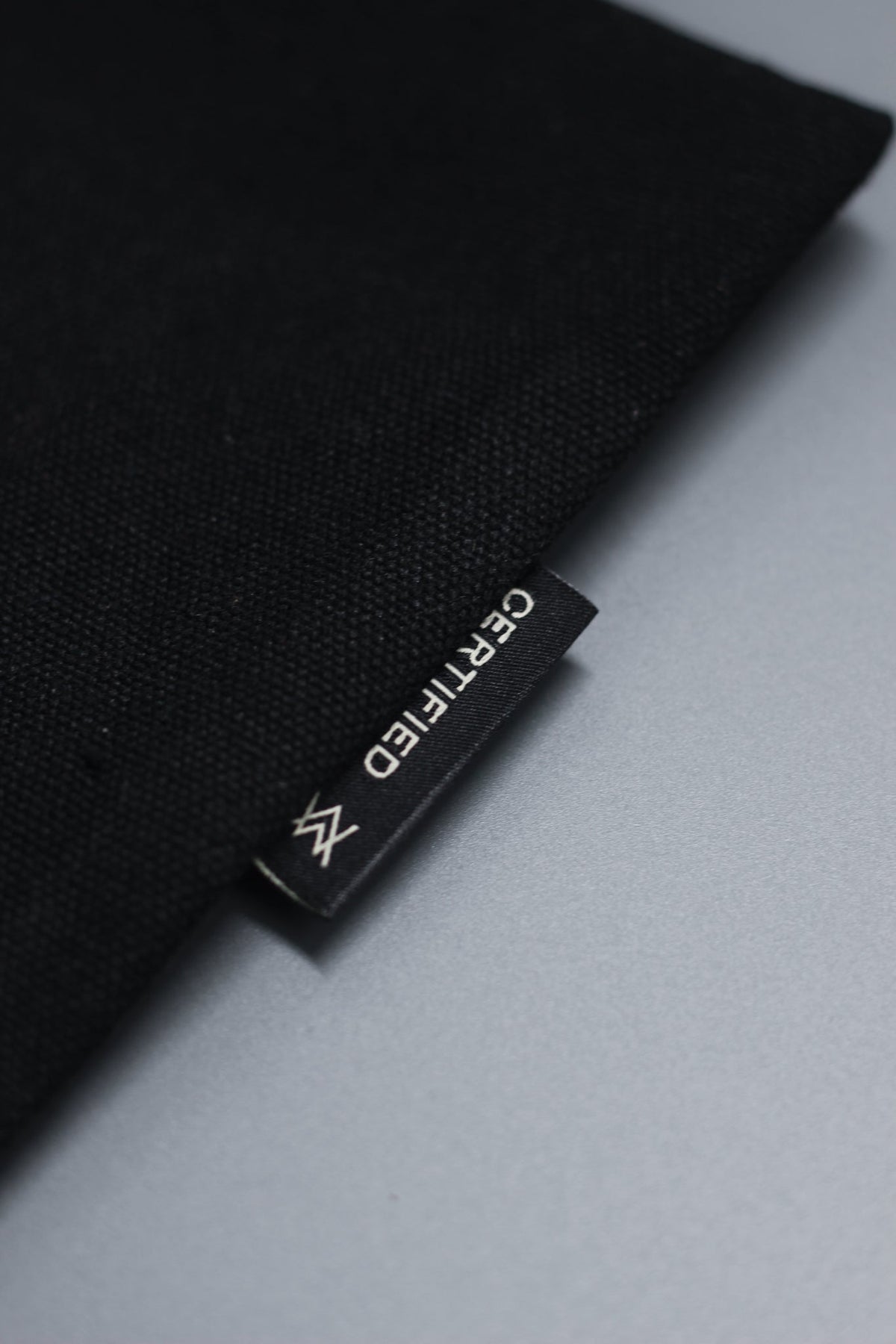 Alan Walker Tired Unity Tote fabric close-up, woven black tag with AW logo stitched into the seam