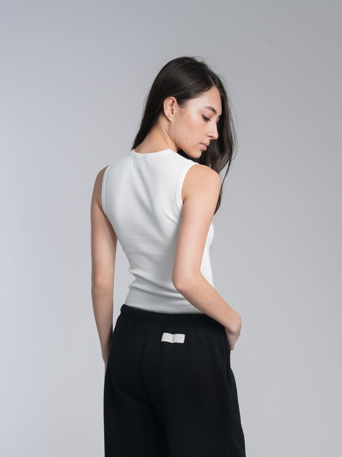 Alan Walker Racer Logo Tank back view on a model, fitted white ribbed tank paired with black joggers