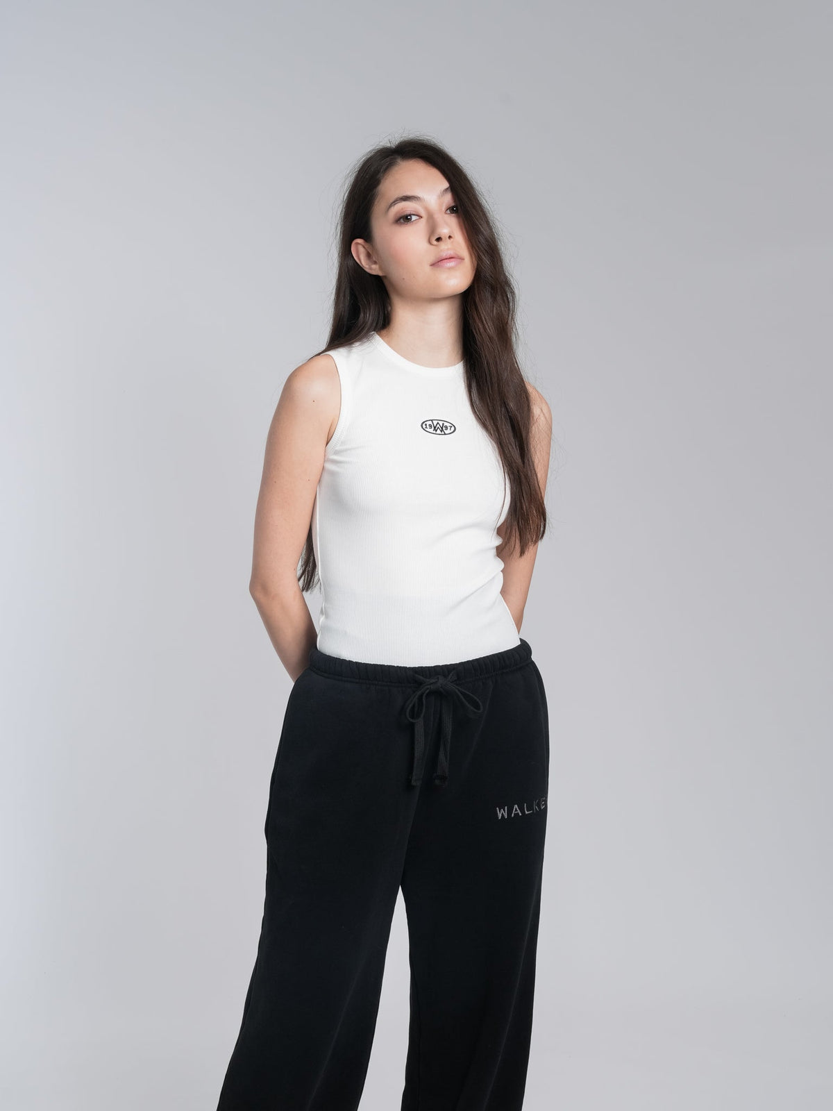 Alan Walker Racer Logo Tank full-length shot on a model, white ribbed tank with black wide-leg Walker pants