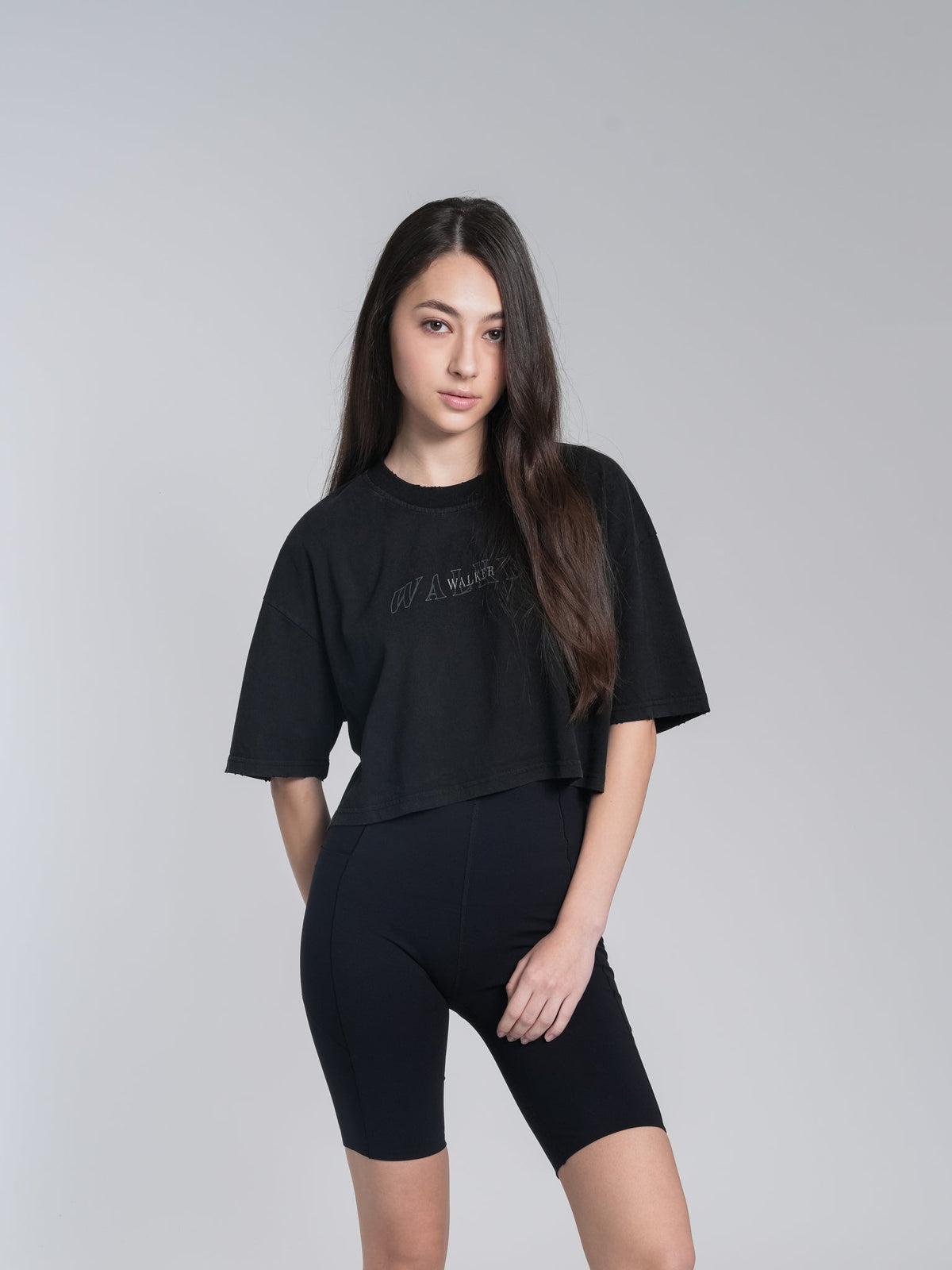 Alan Walker Cropped Tee worn by a model in black, styled with matching black cycling shorts as Walker fan apparel