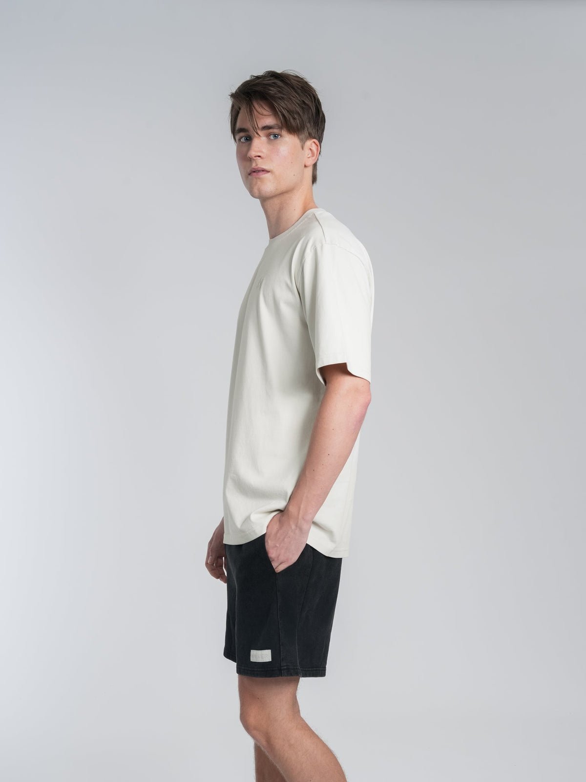 Alan Walker Off-White Walker Tee side profile on a model, drop-shoulder cream tee showing the loose fit