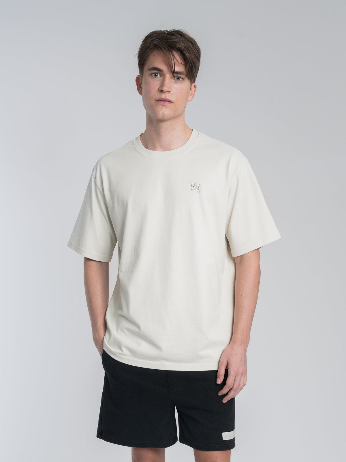 Alan Walker Off-White Walker Tee on a model with hands in pockets, relaxed cream tee and black shorts