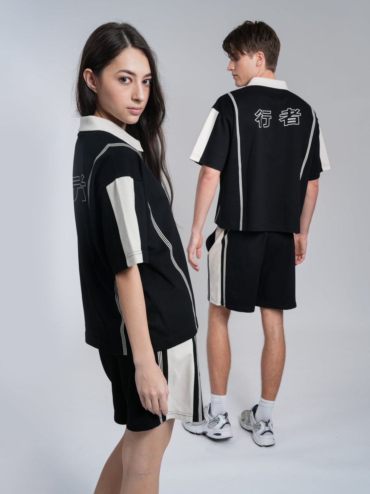 Alan Walker Polo Shorts on two models, front and back views of the black and cream striped co-ord set