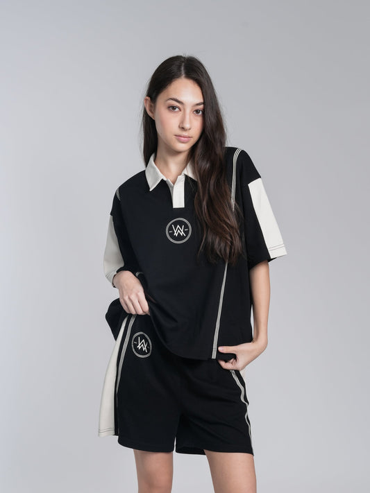 Alan Walker Polo Top front on a model, black boxy polo with cream sleeve panels and circular AW badge