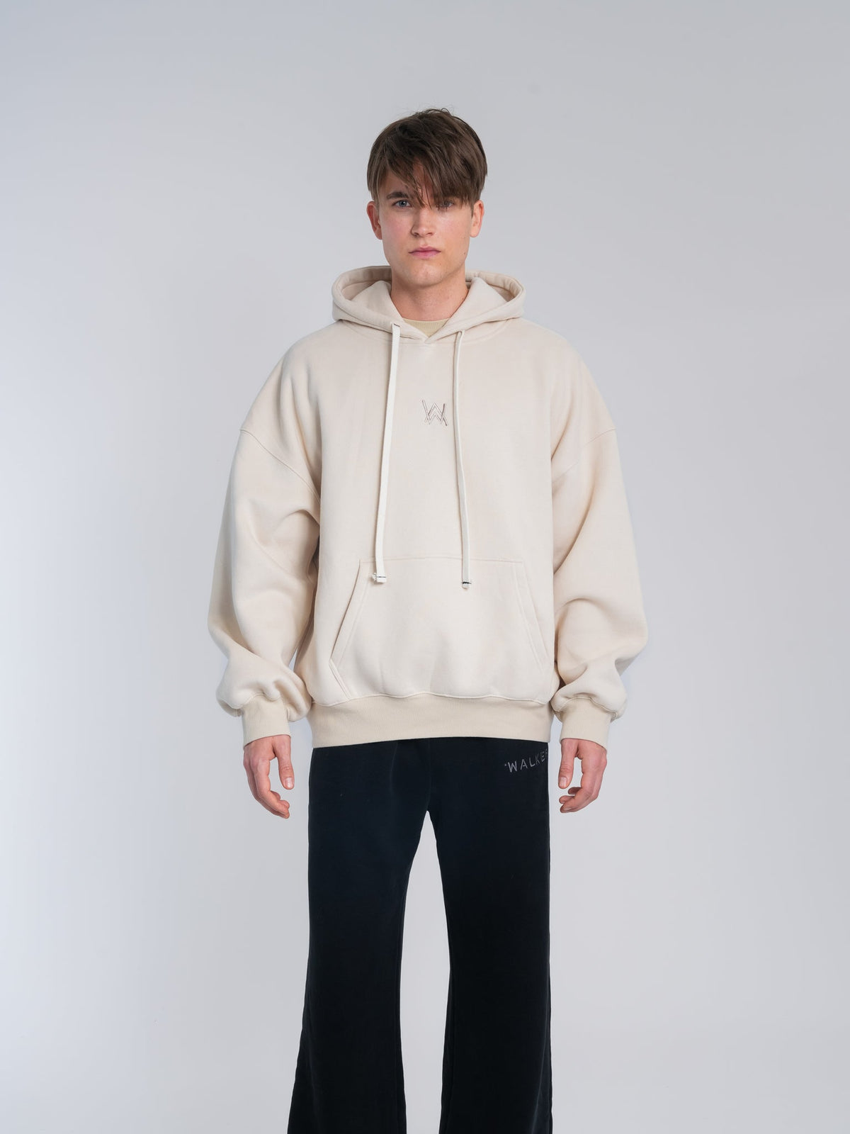 Alan Walker Not Alone Hoodie front view worn by a model, cream hoodie with subtle tonal AW chest logo