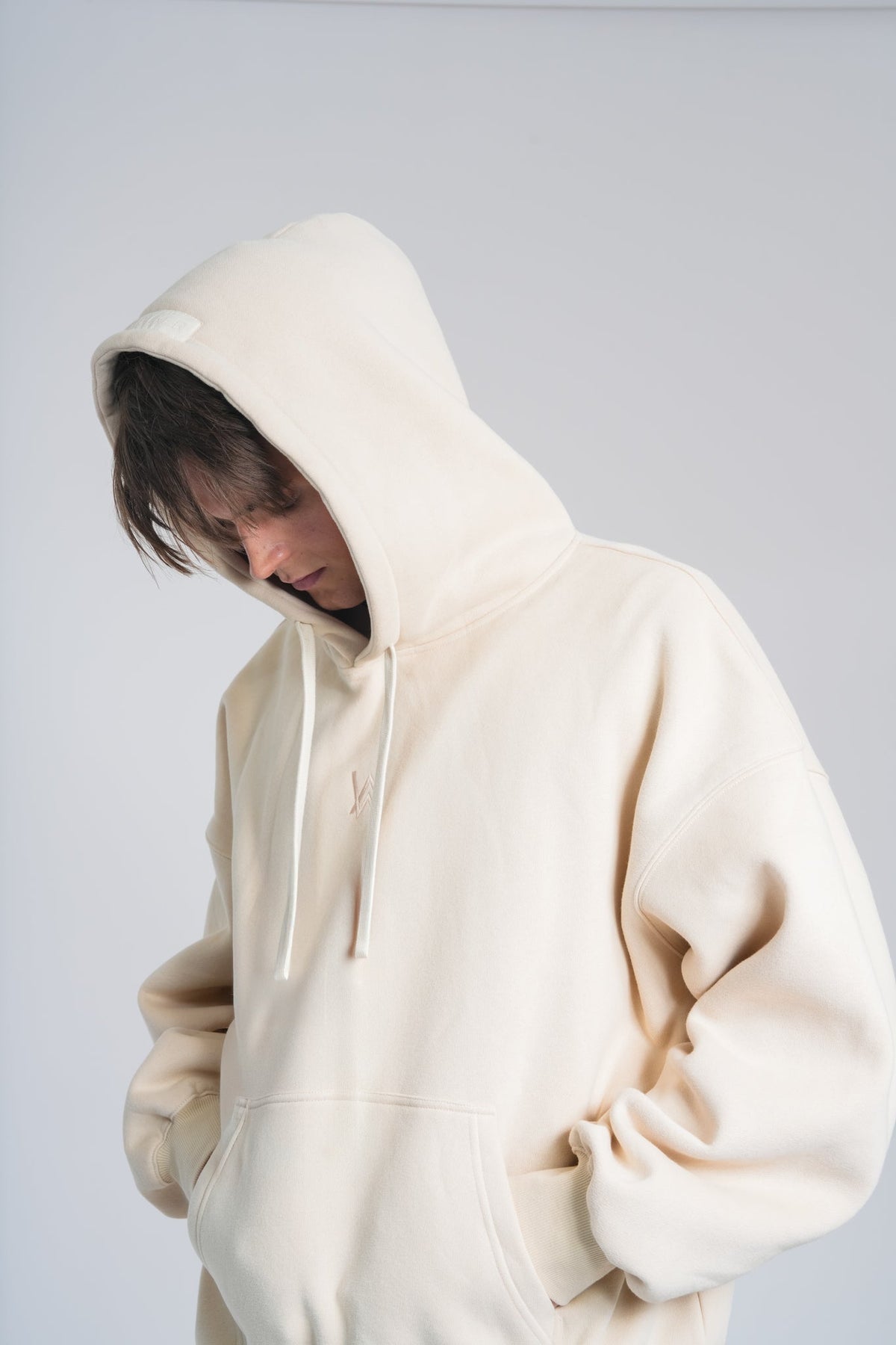 Alan Walker Not Alone Hoodie close-up on a model, cream fleece with drawstring hood and heavy oversized fit