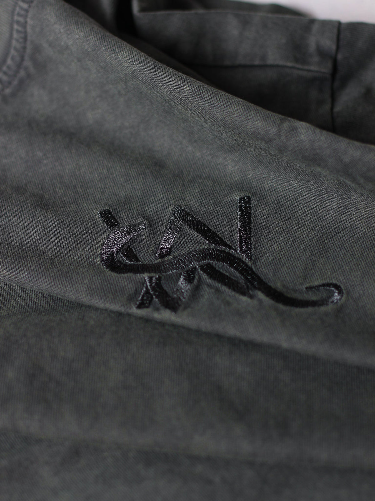 Alan Walker Snake Logo Tee chest detail, raised tonal snake logo embroidery on washed olive green cotton