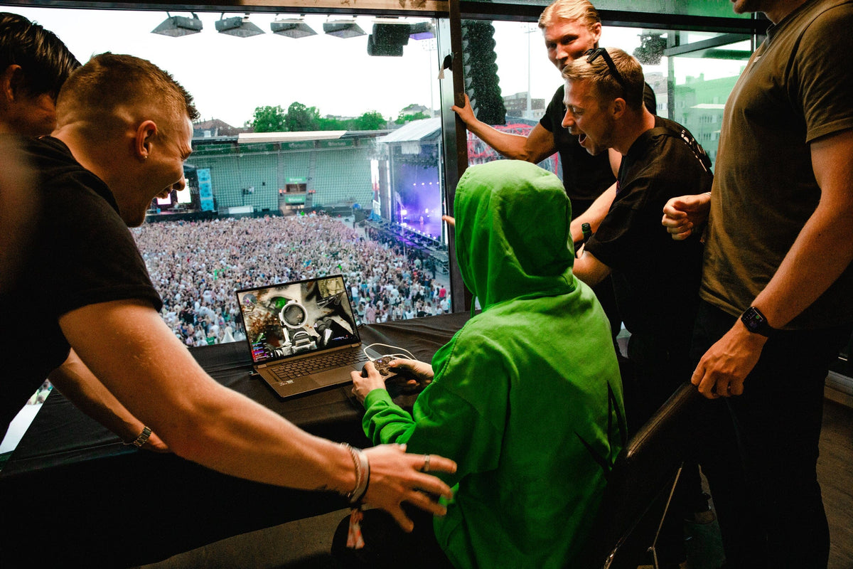 Alan Walker Stage Hoodie green worn backstage with hood up, crew gathered by the stage overlooking fans