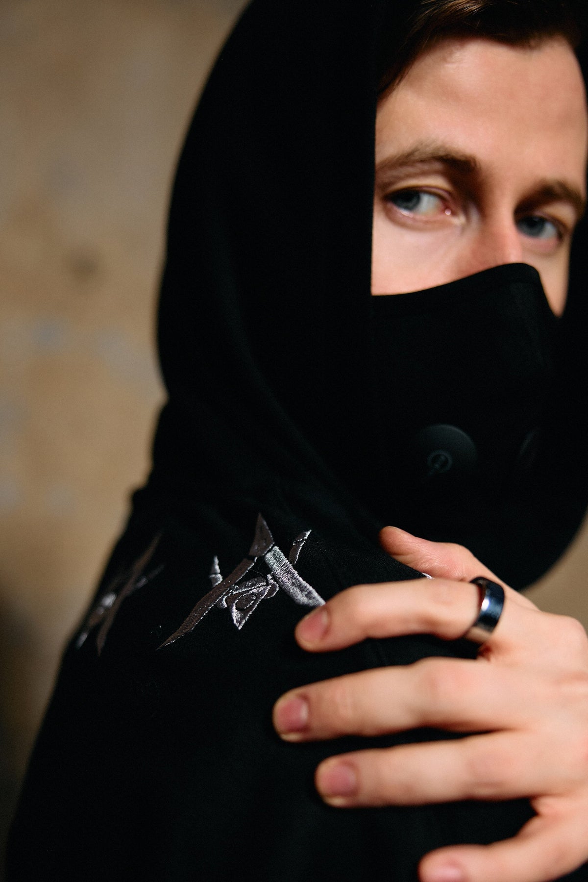 Alan Walker Watch The Drone Hoodie close-up on a model pulling the collar over his face, silver drone print