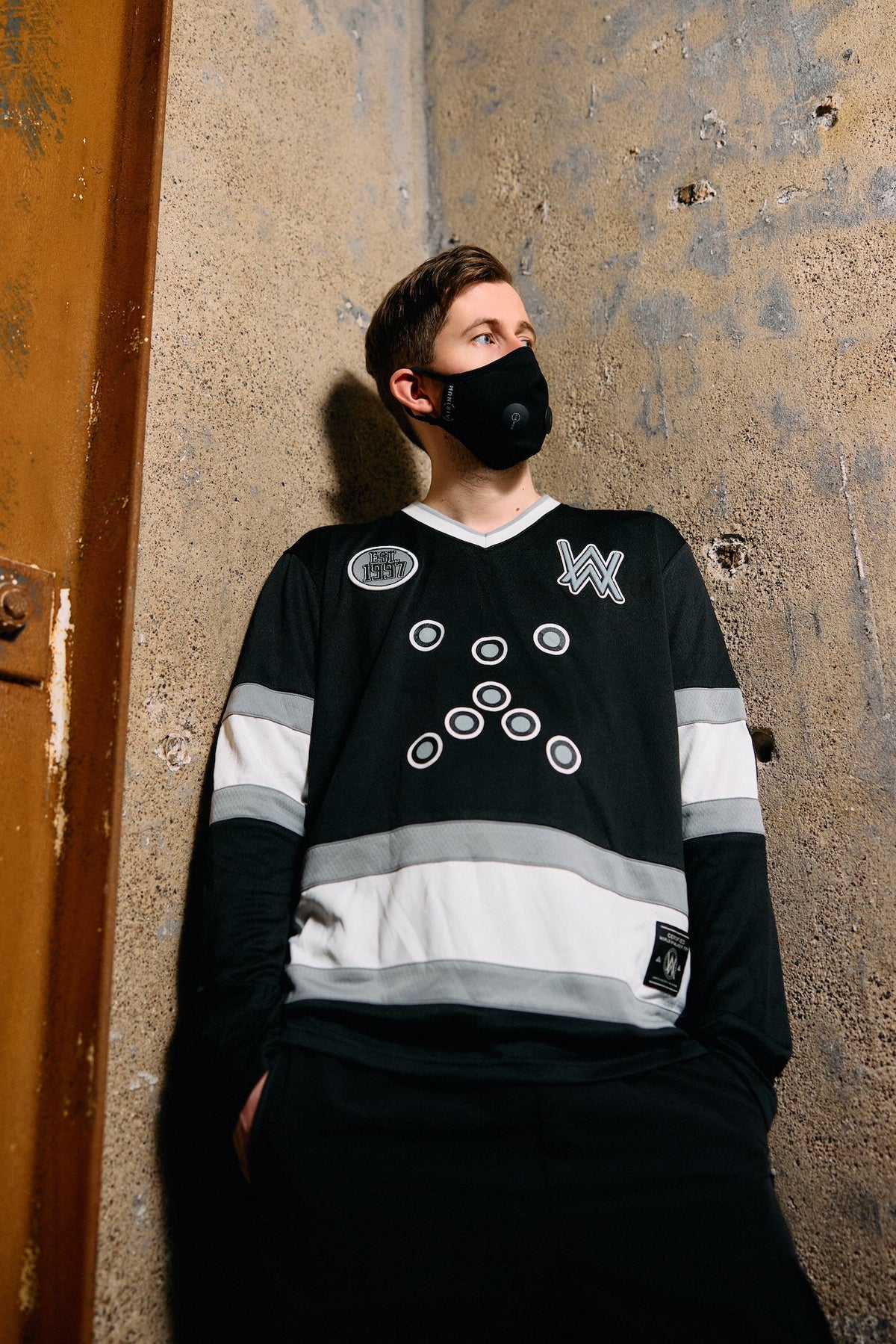 Alan Walker 0 Hockey Jersey lifestyle shot, masked fan in the long-sleeve black jersey against concrete