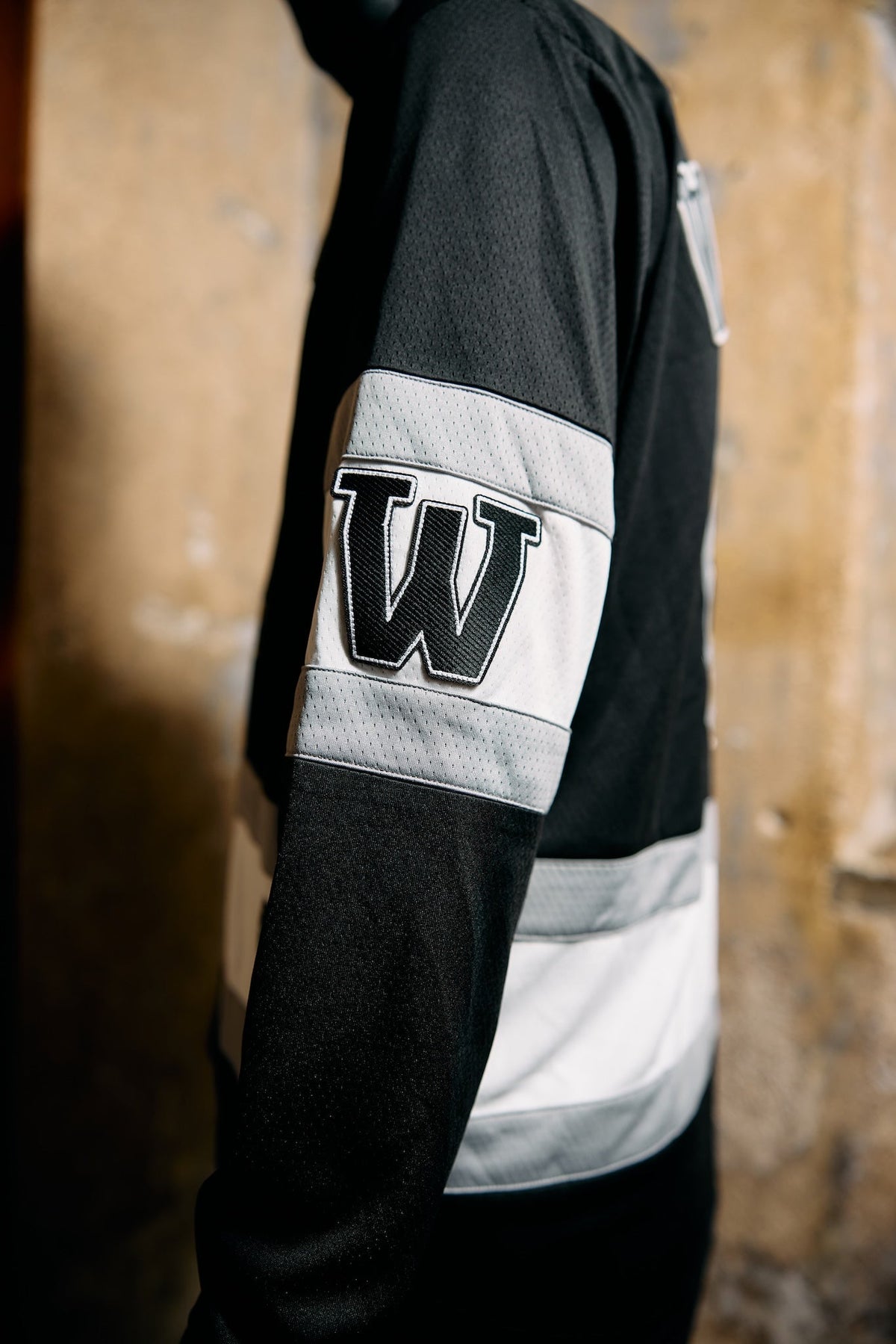 Alan Walker 0 Hockey Jersey sleeve on a model, white striped cuff panel with the black W varsity patch