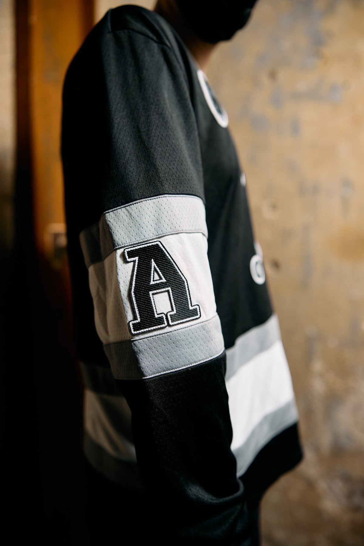 Alan Walker 0 Hockey Jersey worn by a masked model, side profile showing the A patch on the striped sleeve