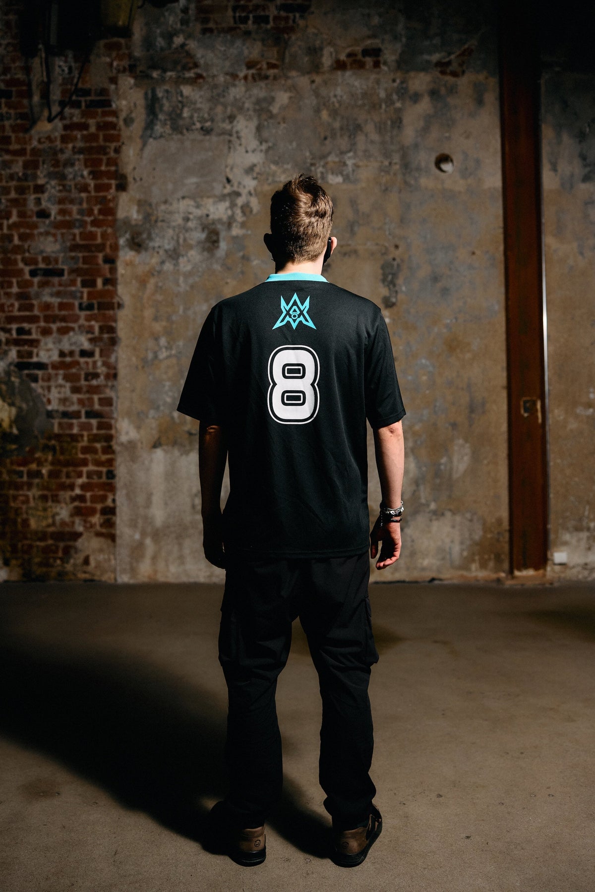 Alan Walker Unity Force Tribe Jersey back on a model by a brick wall, cyan crest over the white number 8