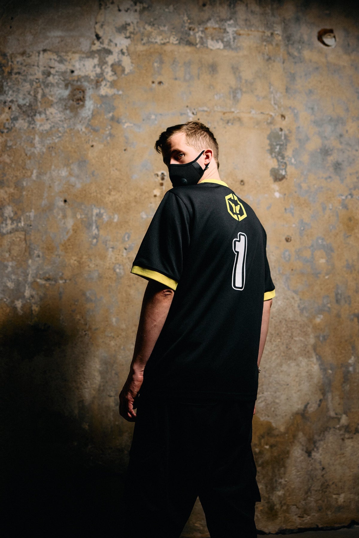 Alan Walker CheckPoint One Tribe Jersey worn by a masked fan outdoors, back view with the number 1 print