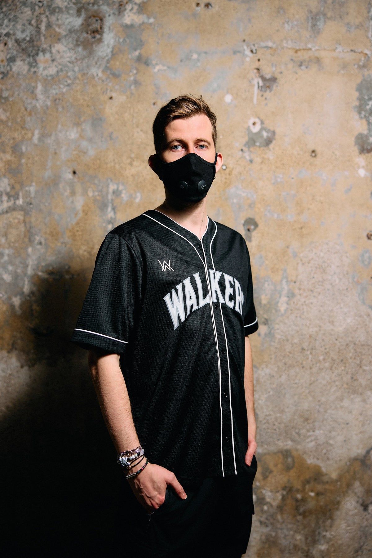 Alan Walker 8 Baseball Jersey lifestyle shot, masked fan wearing the black button-up jersey by a wall