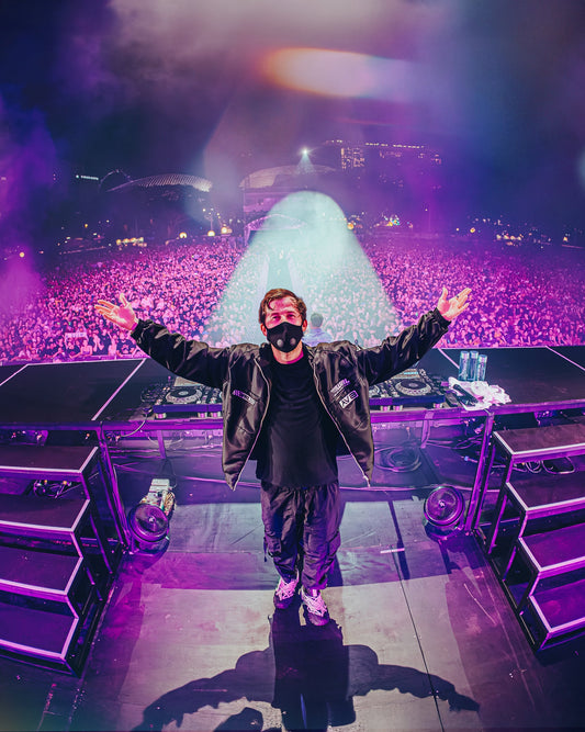 Alan Walker F1 Stage Jacket worn on stage by the masked DJ, arms raised above a purple-lit festival crowd