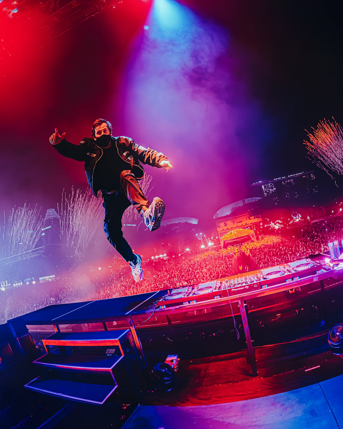 Alan Walker F1 Stage Jacket in action, masked DJ leaping on stage above a red and purple lit crowd