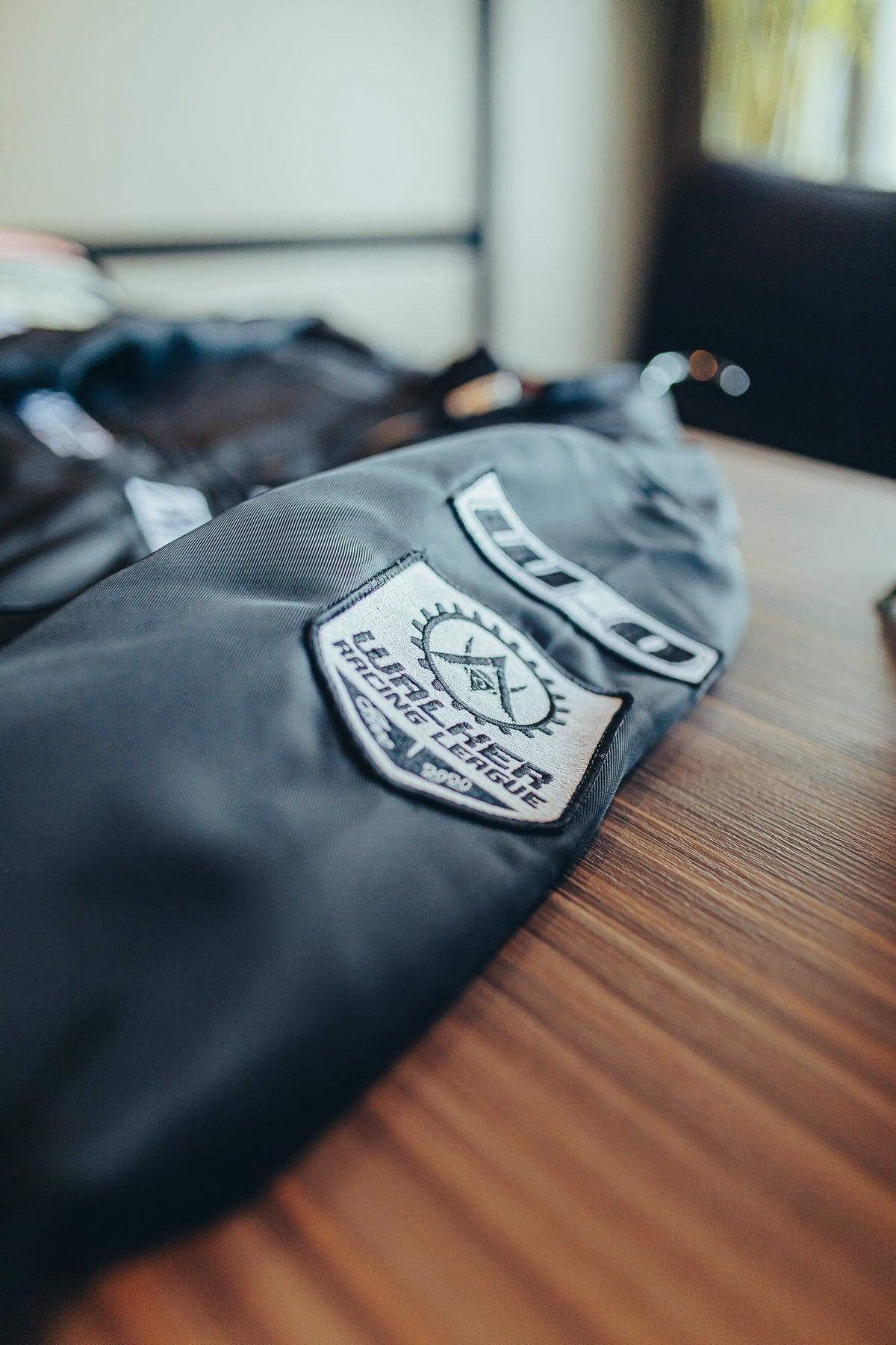 Alan Walker F1 Stage Jacket folded on a wooden table, racing league sleeve patch and zip detail in view