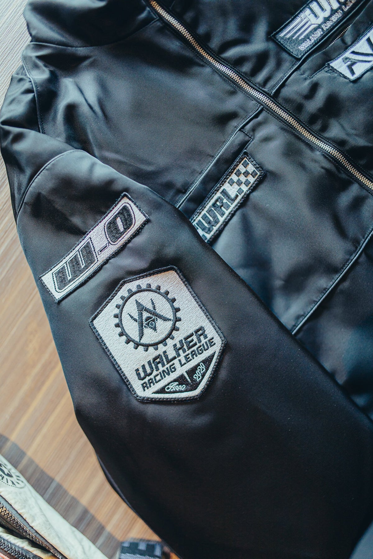 Alan Walker F1 Stage Jacket sleeve close-up, embroidered Walker Racing League and W0 patches on black satin