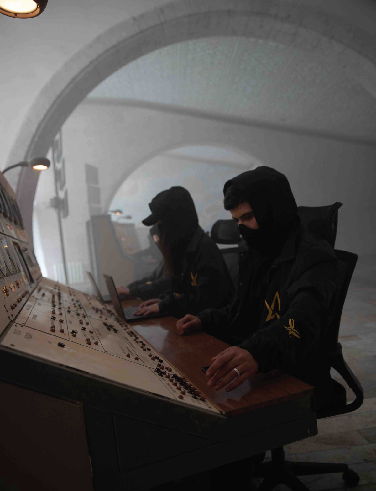 Alan Walker Walkerverse Crew Jacket lifestyle shot, two hooded Walker crew members at a studio console in black jackets