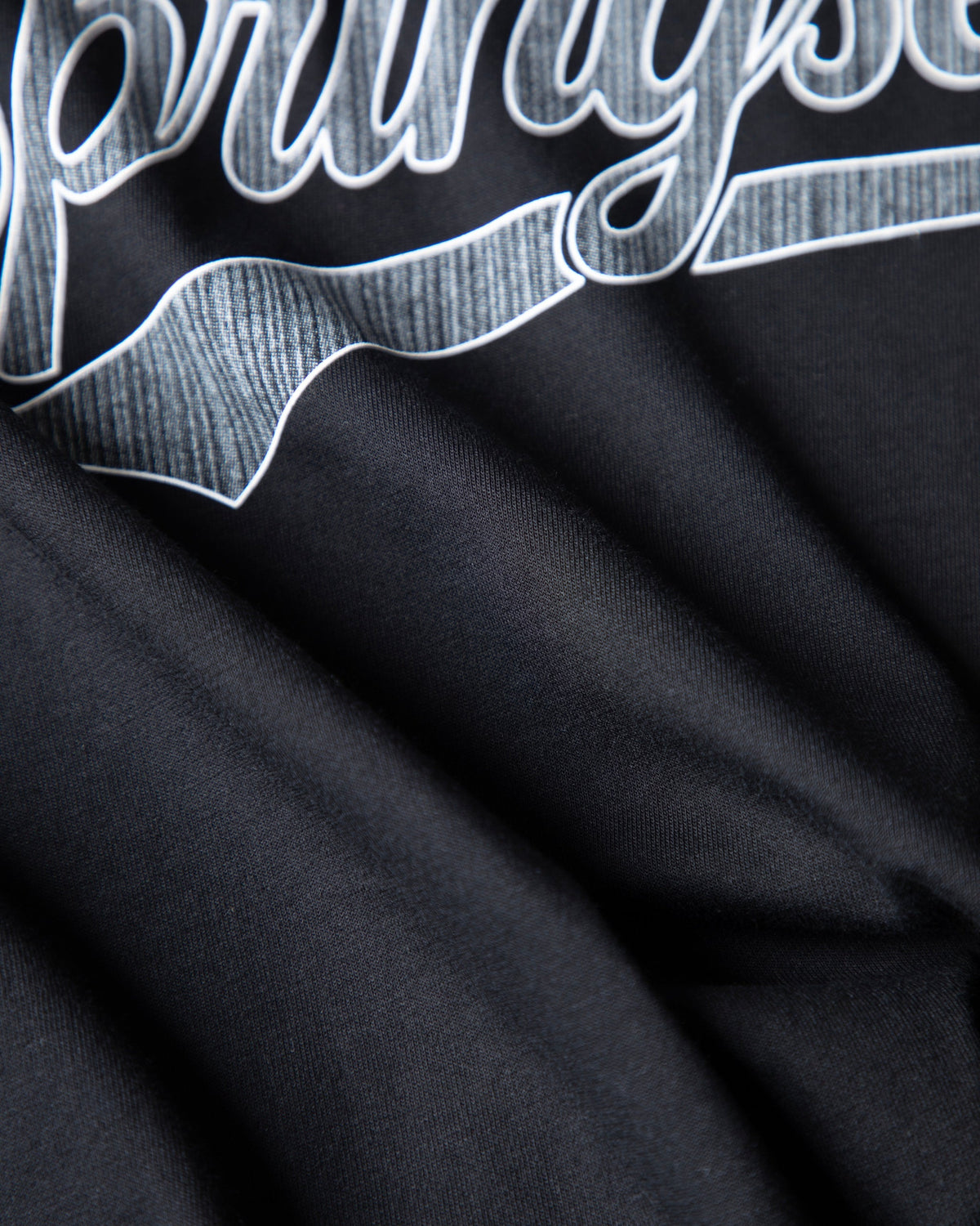 Alan Walker Springseeker Sports T-Shirt macro of the chest print, textured silver script on black sports fabric