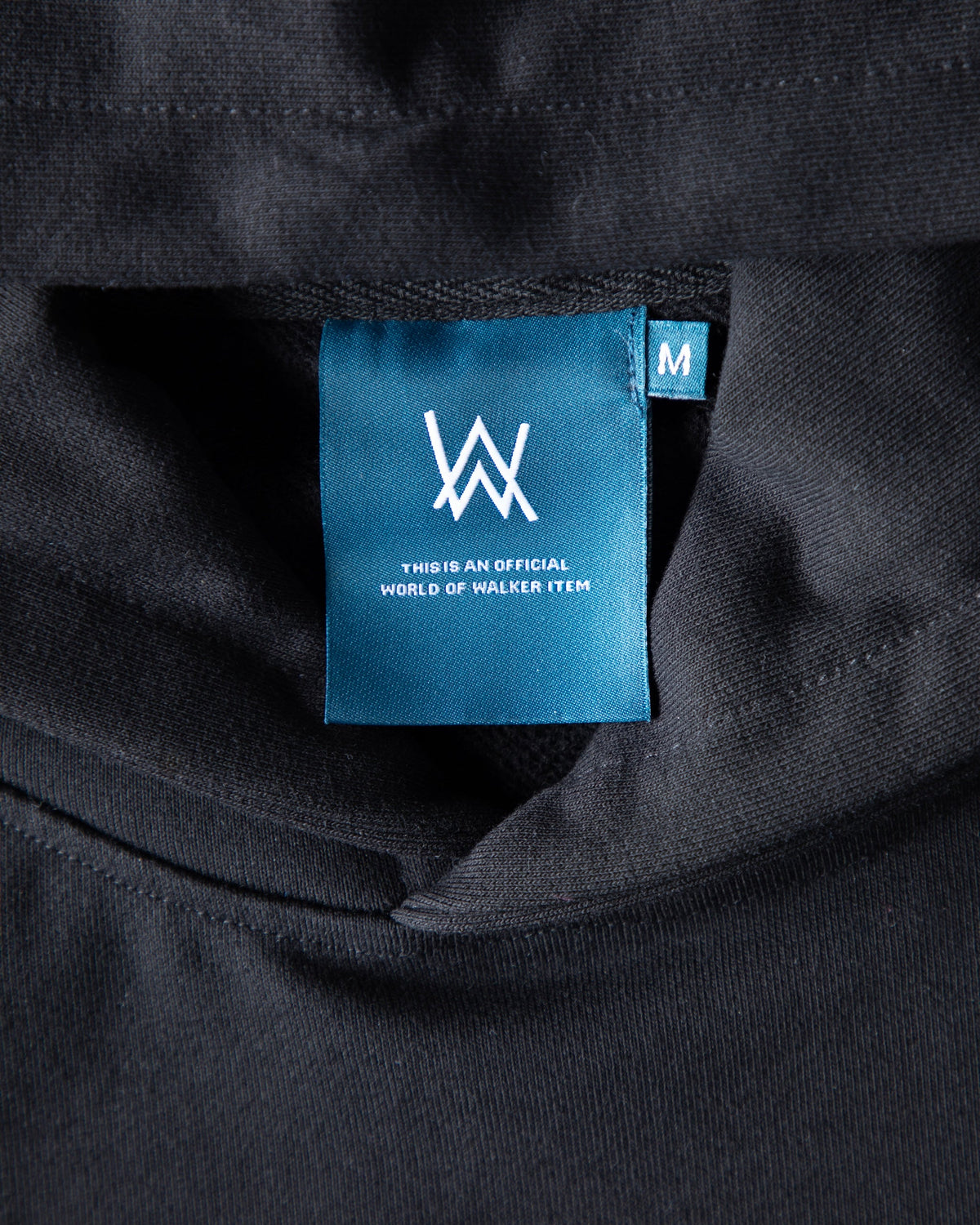 Alan Walker Atlantis 0 Hoodie neck label detail, teal woven World of Walker tag in size M on black fleece