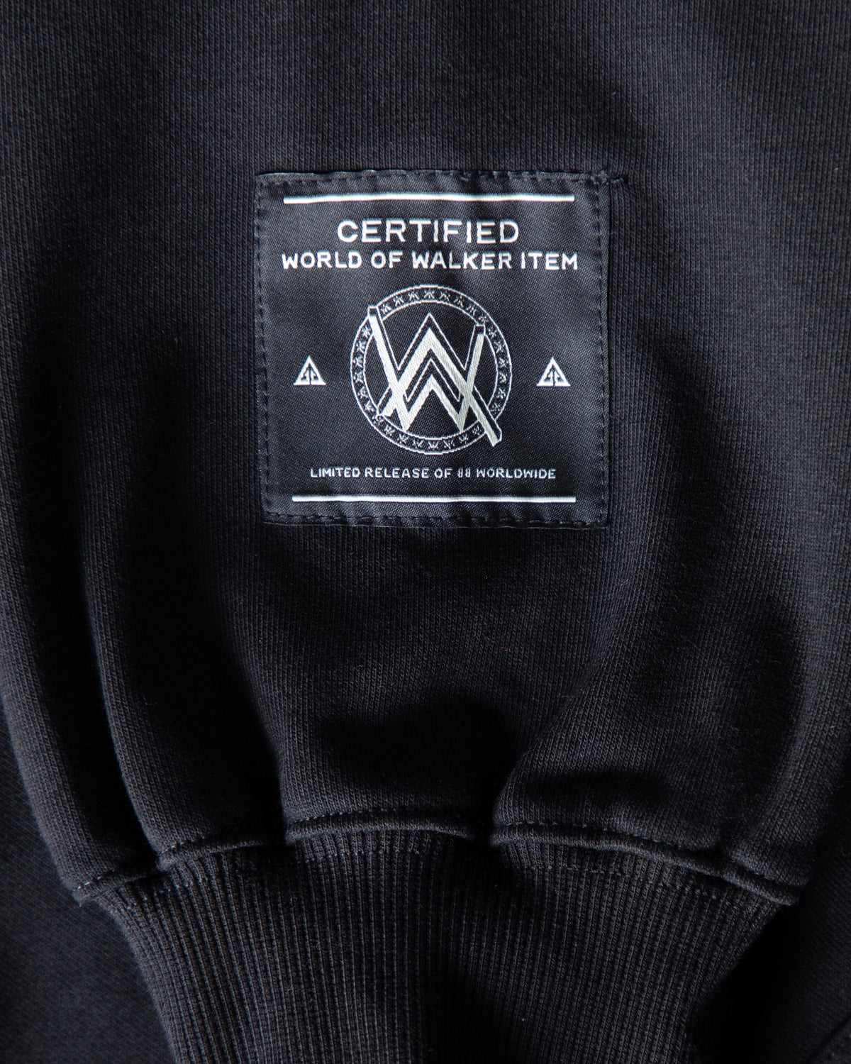 Alan Walker Atlantis 0 Hoodie hem close-up, woven World of Walker label above the ribbed black hem