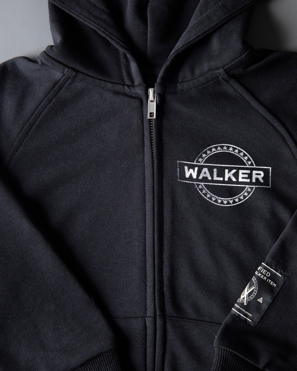 Alan Walker Monster Core Kids Zip Hoodie chest print close-up from the side, WALKER emblem with the hem tag in view