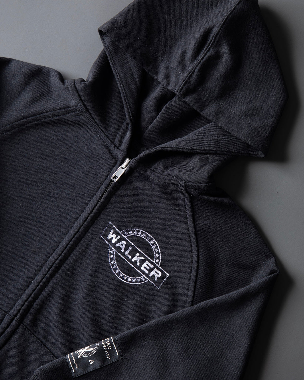 Alan Walker Monster Core Kids Zip Hoodie angled flat lay in black, hood at the top and WALKER circle emblem on the chest