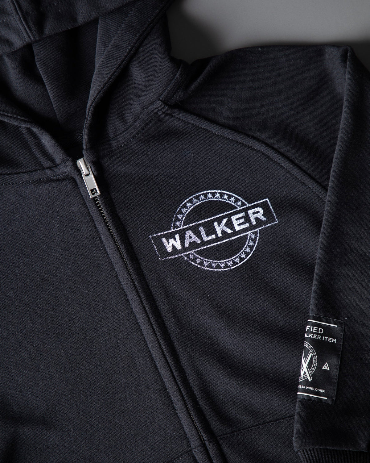 Alan Walker Monster Core Kids Zip Hoodie chest detail, circular WALKER stamp beside the zip with woven side label