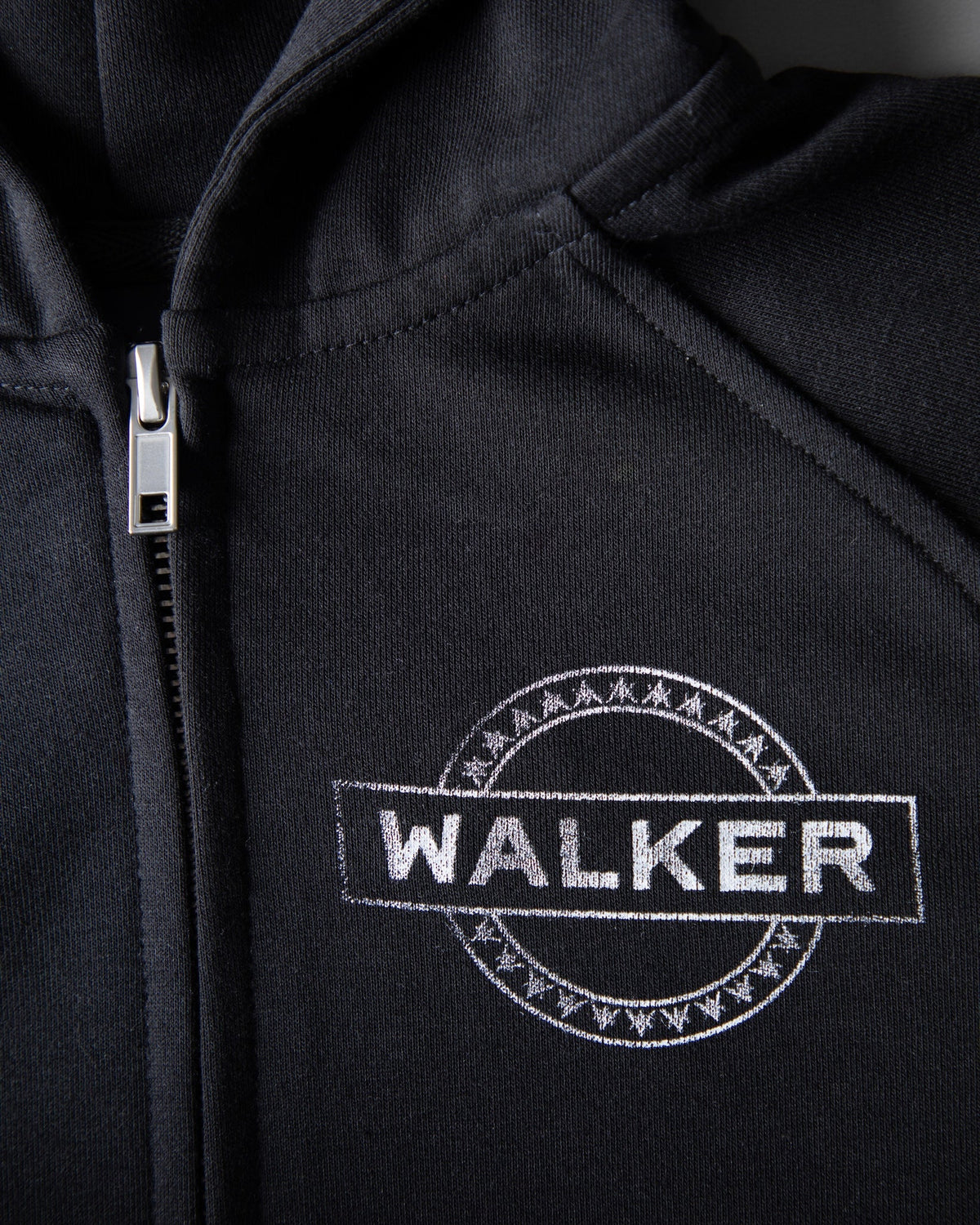 Alan Walker Monster Core Kids Zip Hoodie close-up of the metal zip pull and silver WALKER circle emblem on black fleece
