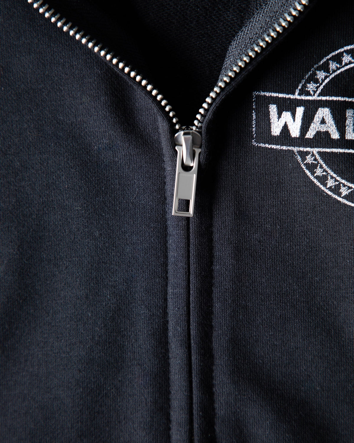 Alan Walker Kids Zip Hoodie detail shot of the metal zipper and woven Walker crest badge on black fleece
