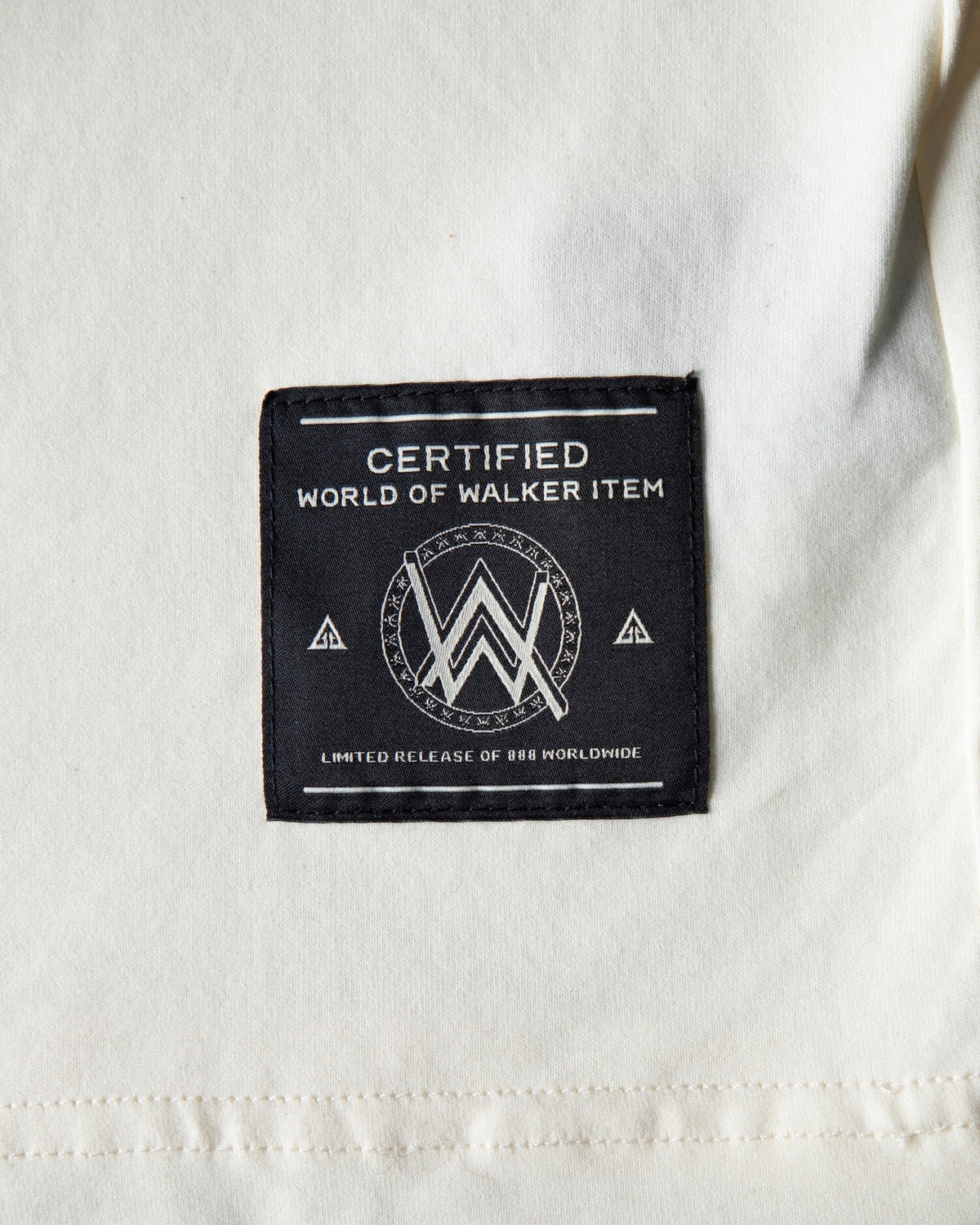 Alan Walker WRL Logo Longsleeve hem tag close-up, World of Walker black woven label on cream