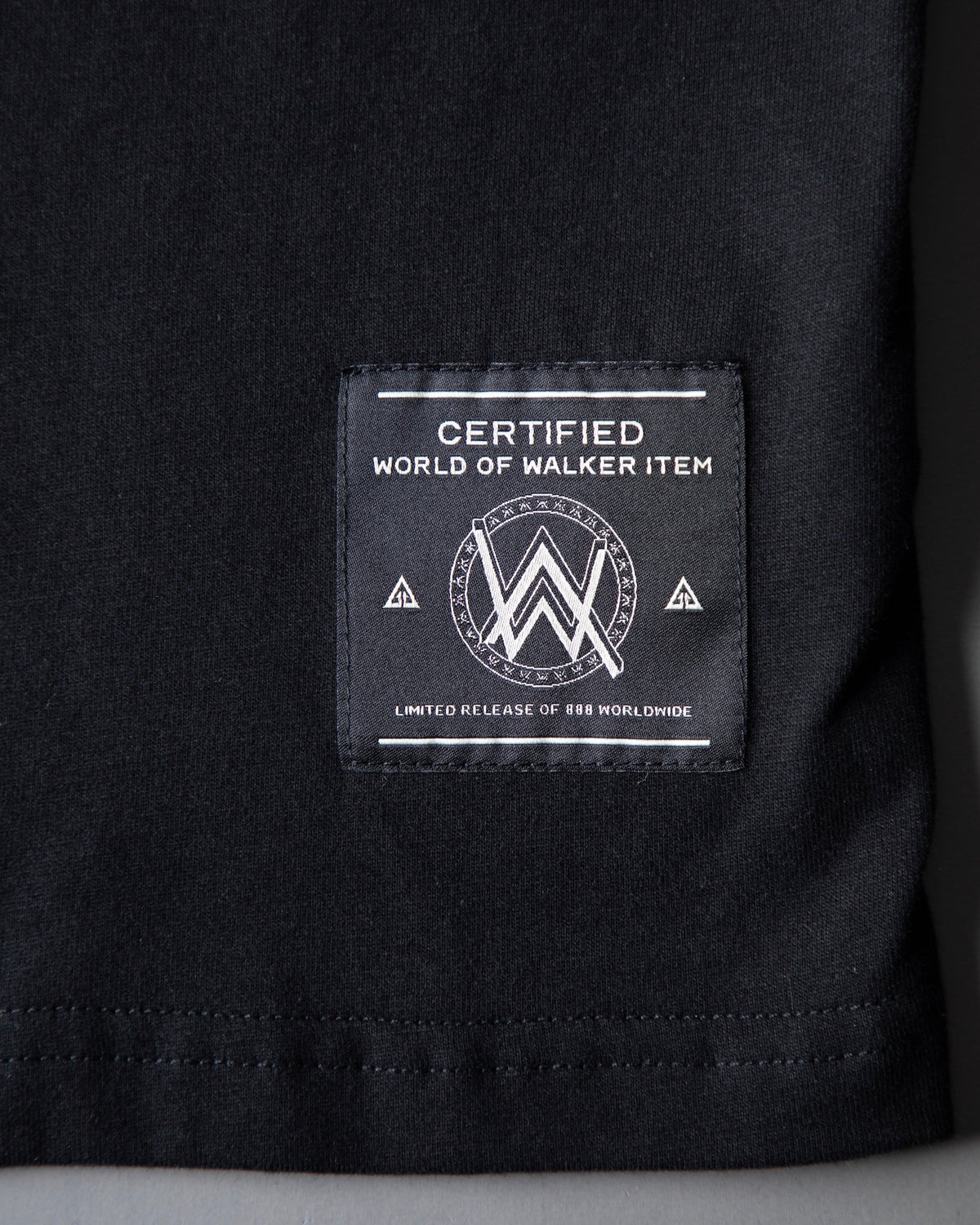 Alan Walker WRL Speed Logo T-shirt hem close-up with the woven World of Walker label on black cotton