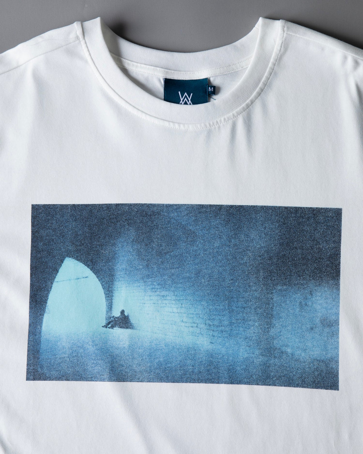 Close-up of the Faded Play T-shirt chest print, the faded blue tunnel artwork with a lone seated figure