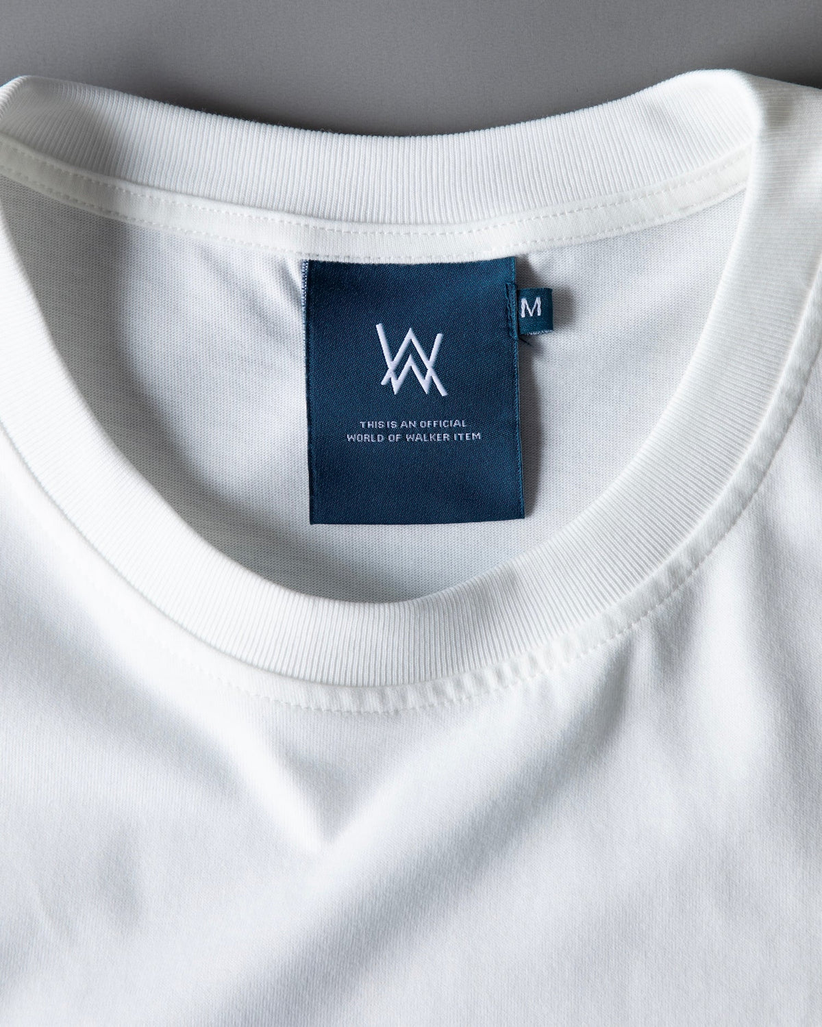 Inside neck label of the Faded Play T-shirt, a navy tag with the AW monogram and size M marking