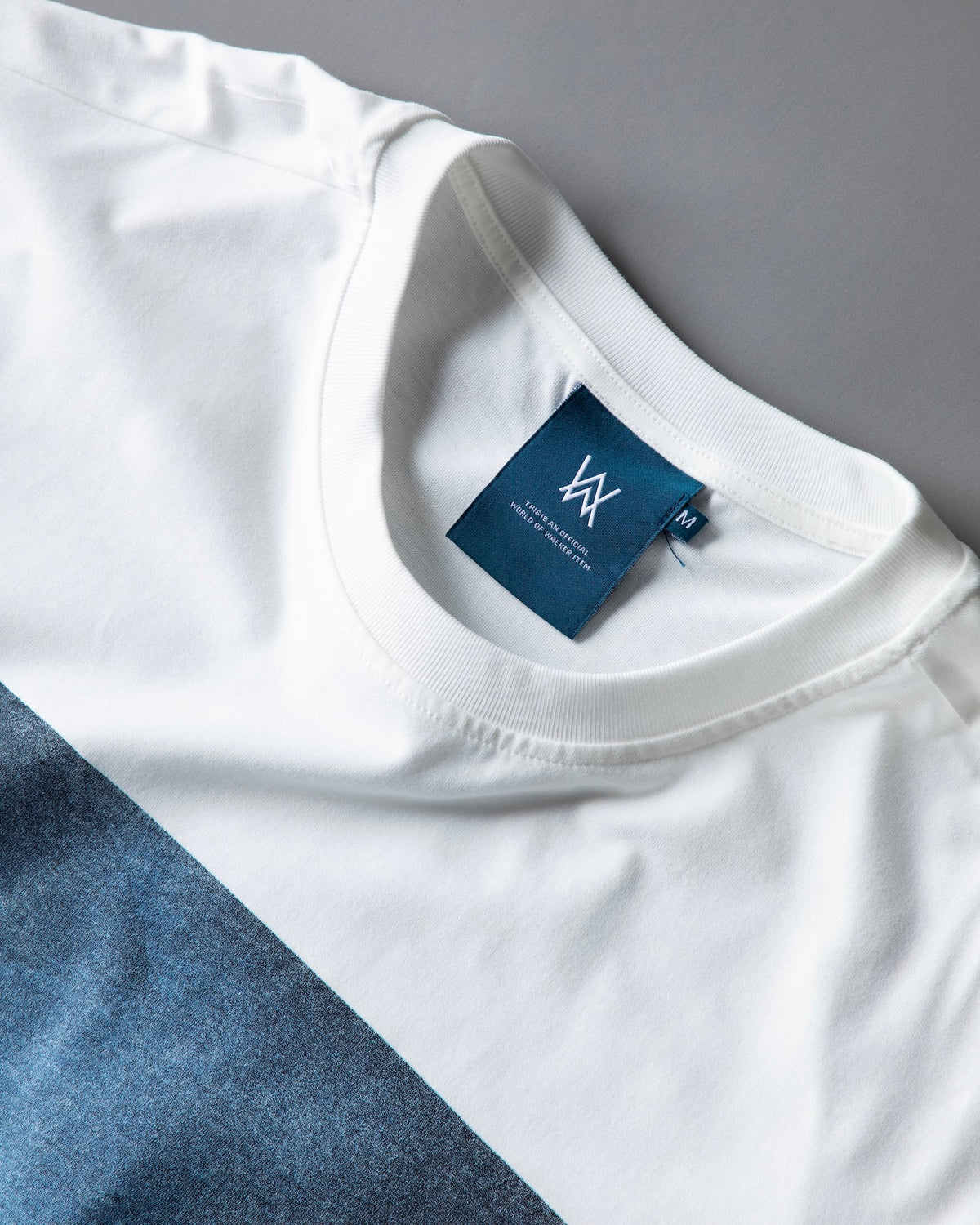 Angled collar shot of the Faded Play T-shirt with the navy AW neck tag and the blue chest print visible