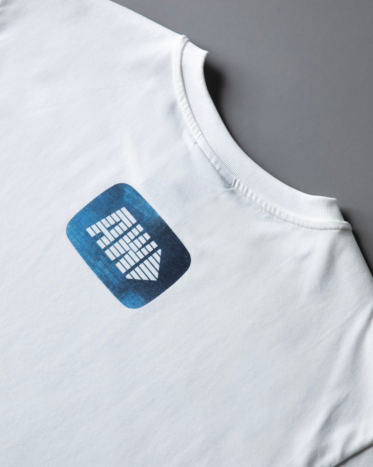 Shoulder and back detail of the white Faded Play T-shirt with the blue AW arrow logo print