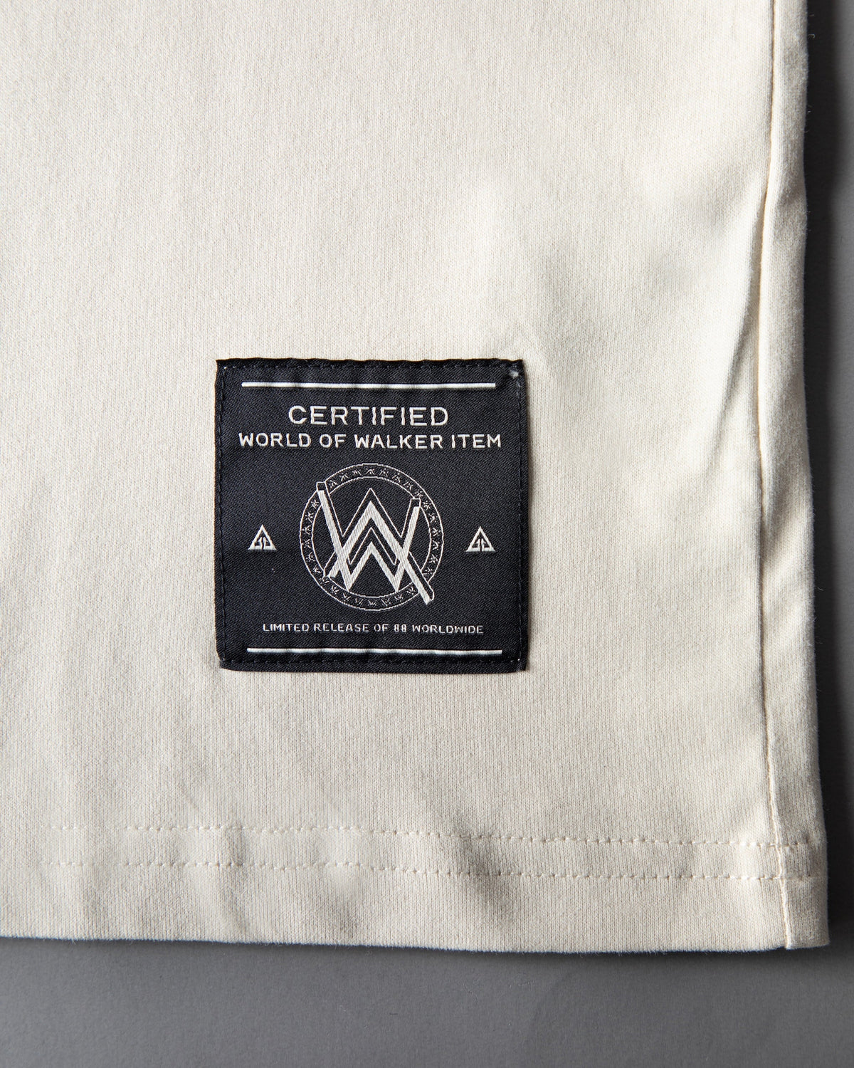 Alan Walker Encyclopedia T-Shirt cream hem close-up with the black woven World of Walker label