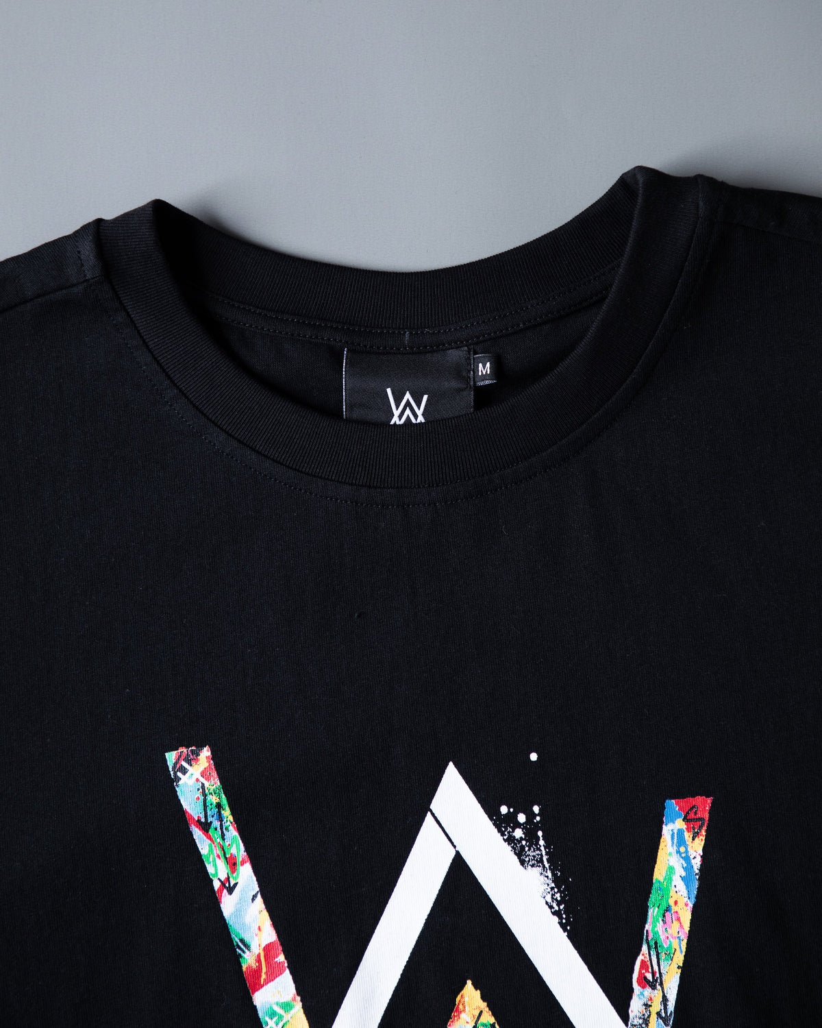 Alan Walker Tired 0 Tee neckline detail, AW size label above the floral-fill logo print on black cotton