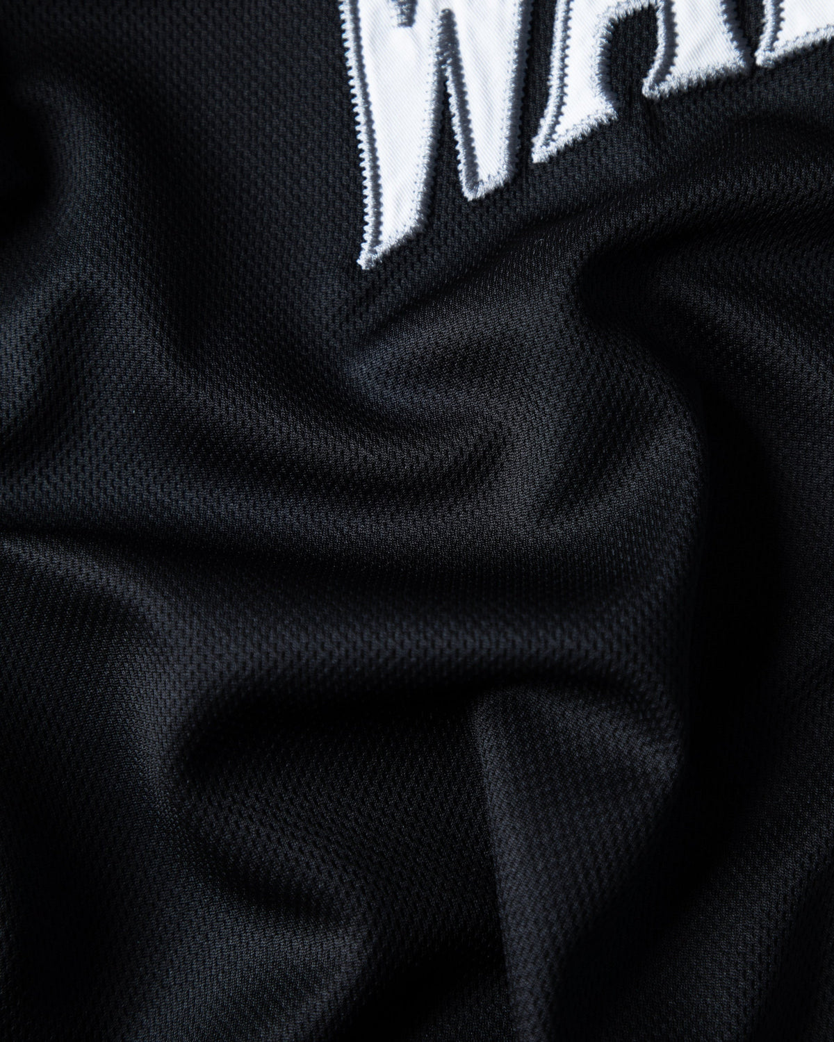 Alan Walker 0 Baseball Jersey fabric close-up showing the stitched white varsity letters on black mesh