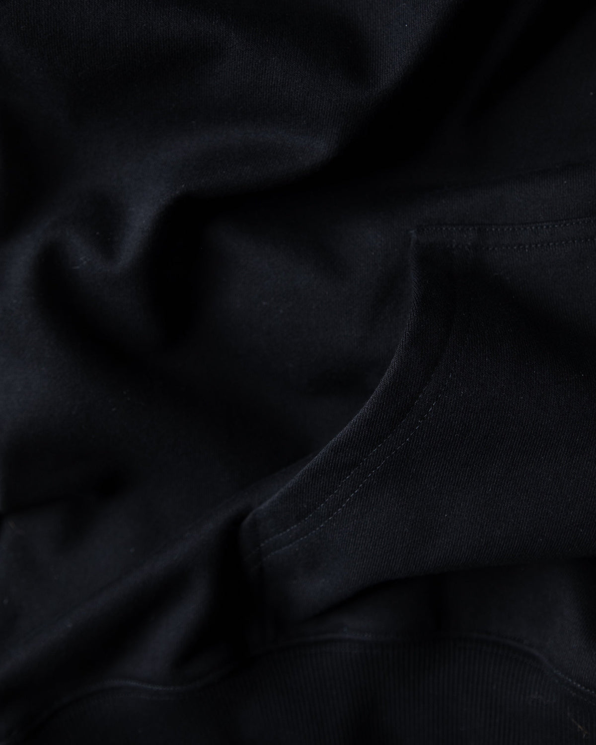 Alan Walker Watch The Drone Hoodie fabric close-up showing the soft black brushed fleece and stitched seams